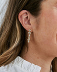 Close-up of a person wearing CZ drop earrings with a blurred background