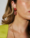 Close-up of a woman wearing red floral earrings with a gold necklace.