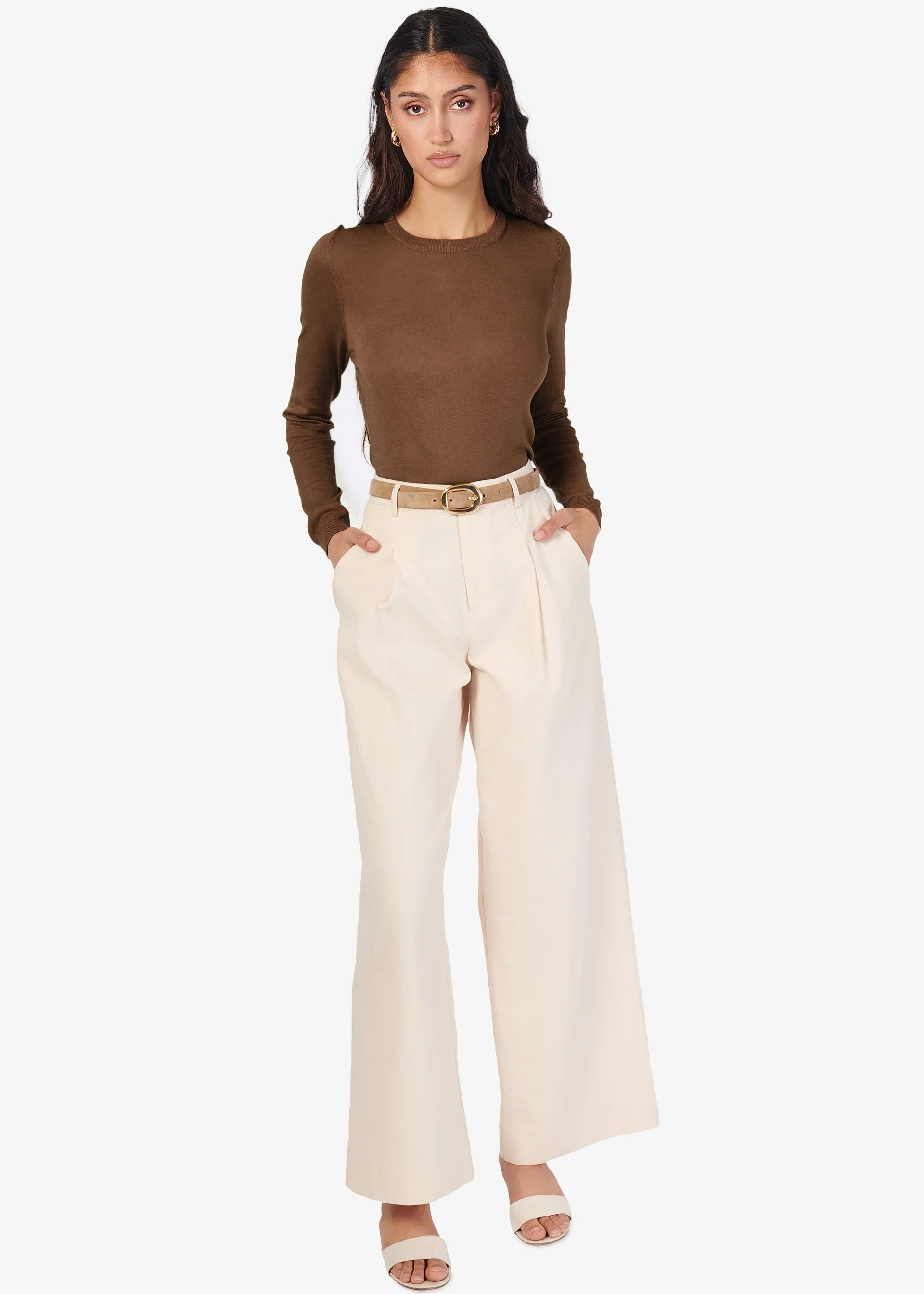 Woman wearing a brown top and beige pants on a white background front view