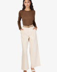 Woman wearing a brown top and beige pants on a white background front view