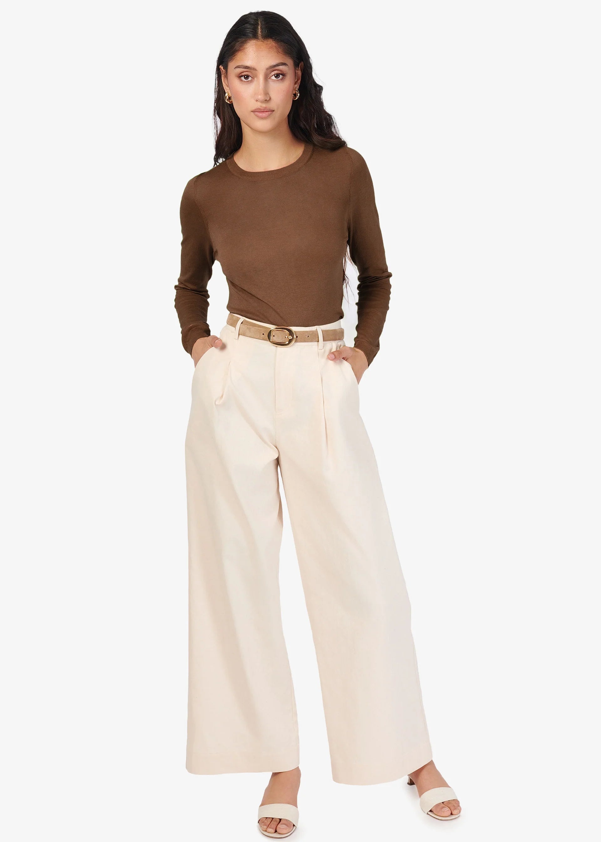 Woman wearing a brown long-sleeve top and beige wide-leg pants on a white background front view