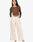 Woman wearing a brown long-sleeve top and beige wide-leg pants on a white background front view