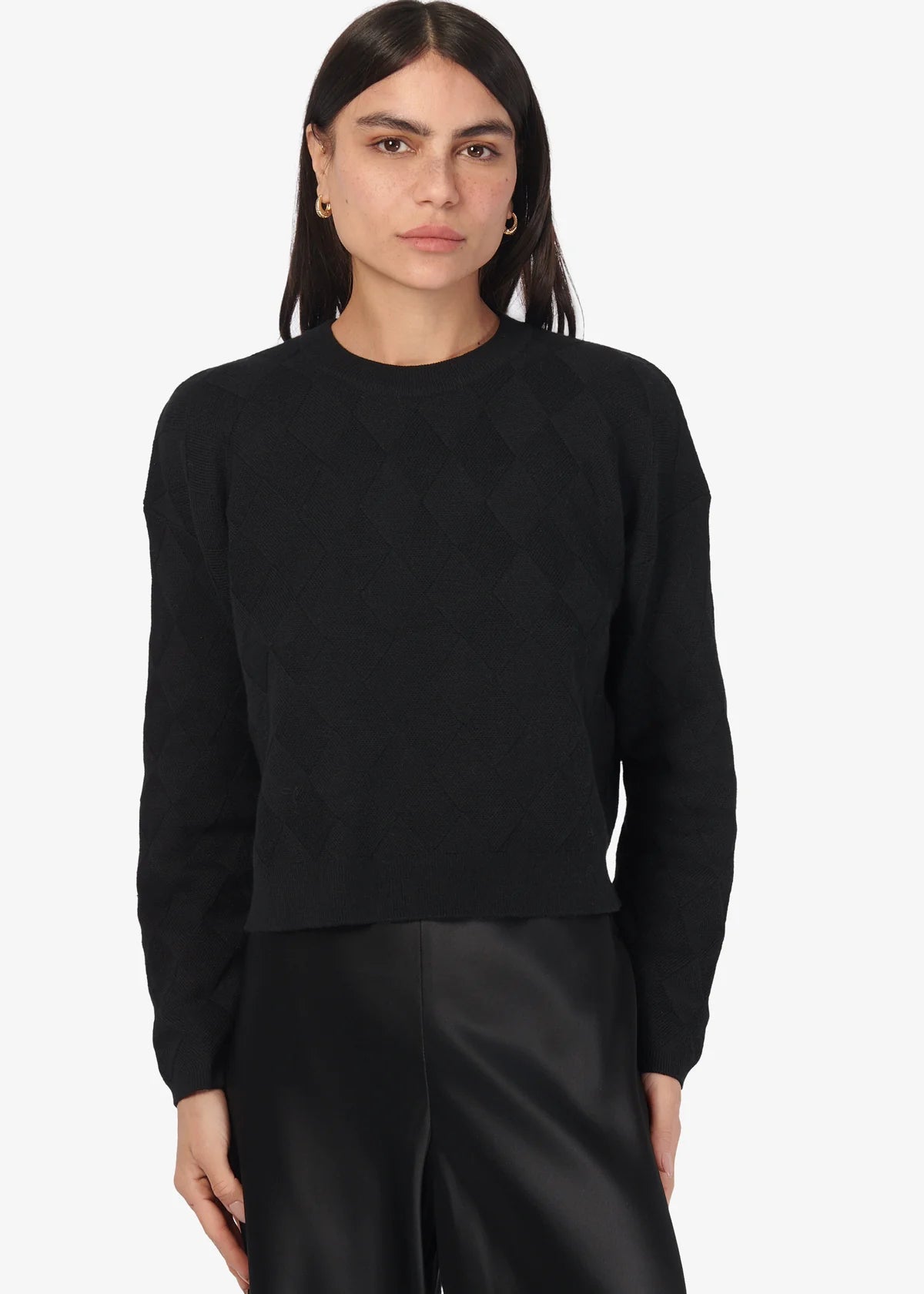 Person wearing a black sweater and pants on a white background