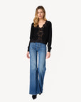 a model wearing a black cardigan with lace trim and blue jeans on a white background