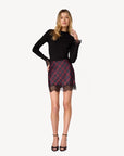 model wearing a long sleeve black top with lace at the wrist with a plaid mini skirt with lace trim on a white background