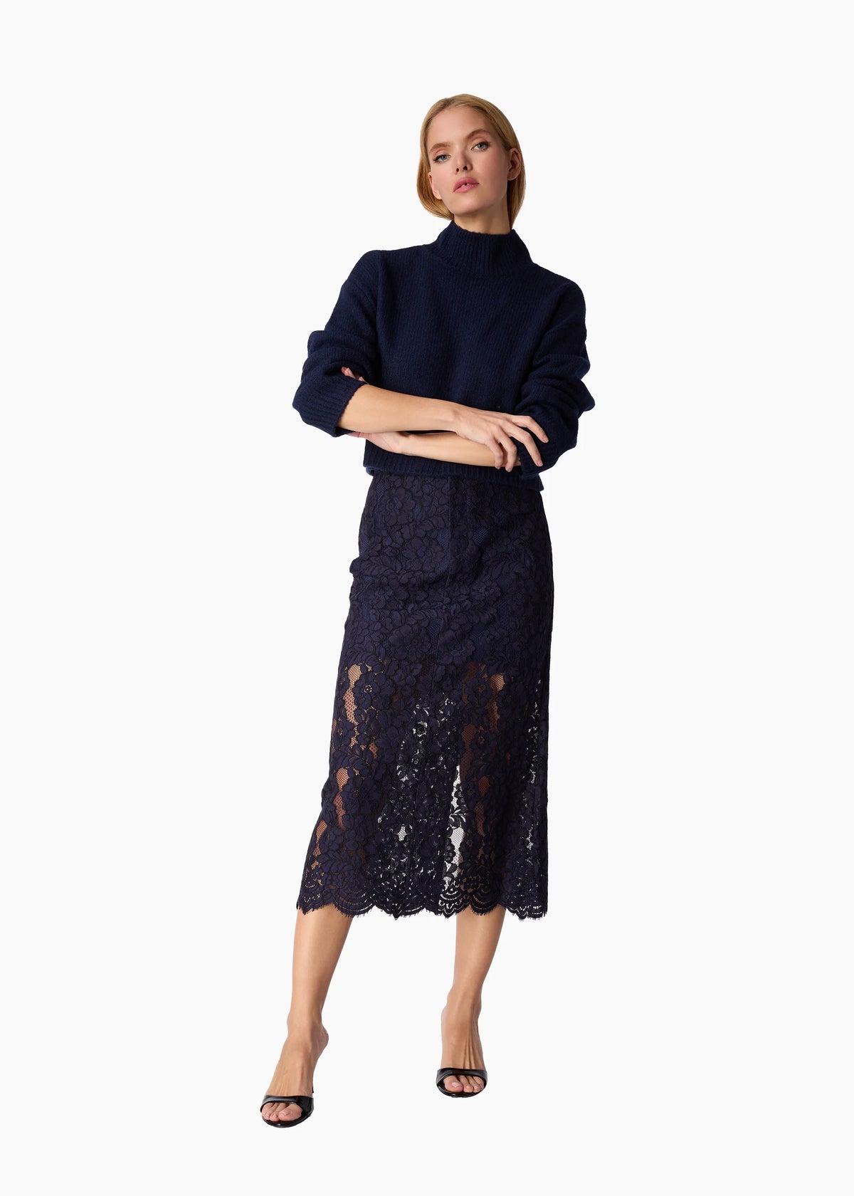 Woman wearing a navy blue outfit with a lace skirt on a white background