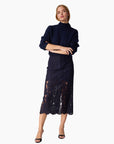 Woman wearing a navy blue outfit with a lace skirt on a white background