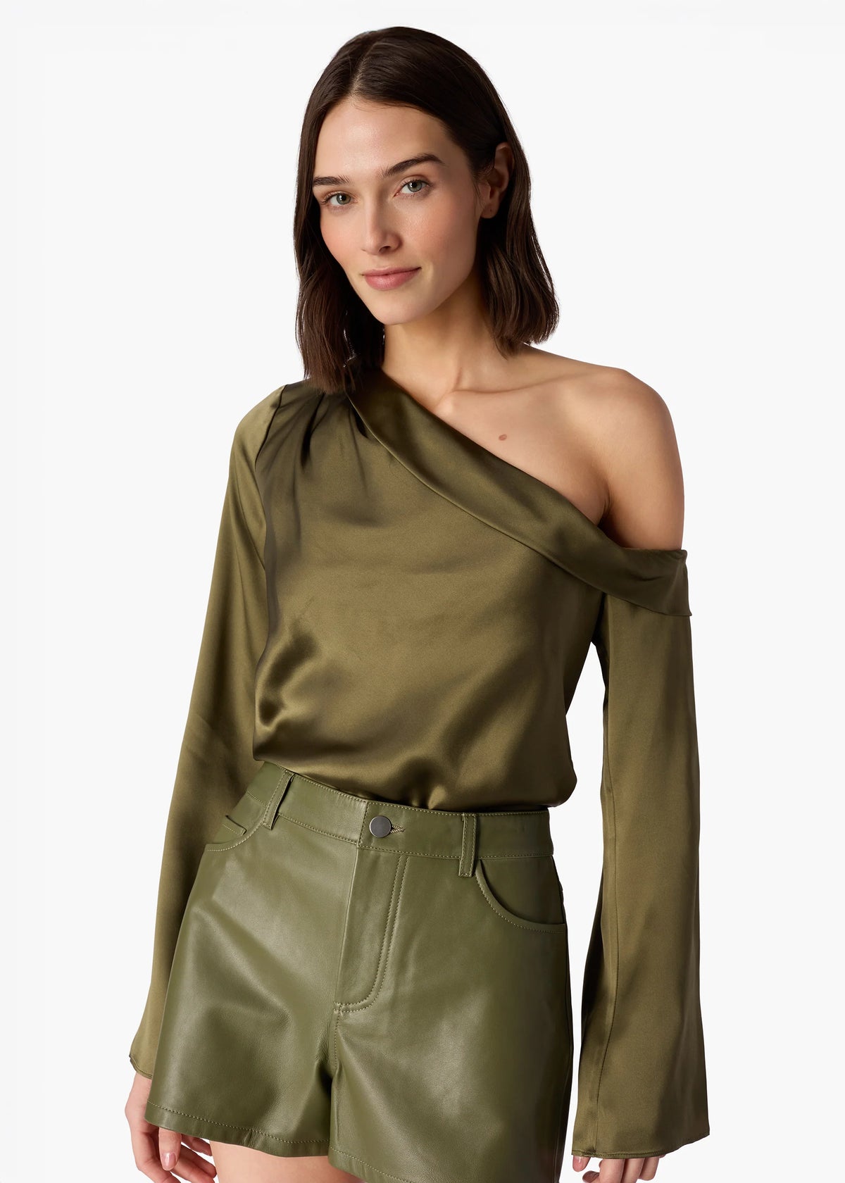 Woman wearing an olive green one-shoulder top and shorts on a white background