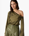 Woman wearing an olive green one-shoulder top and shorts on a white background