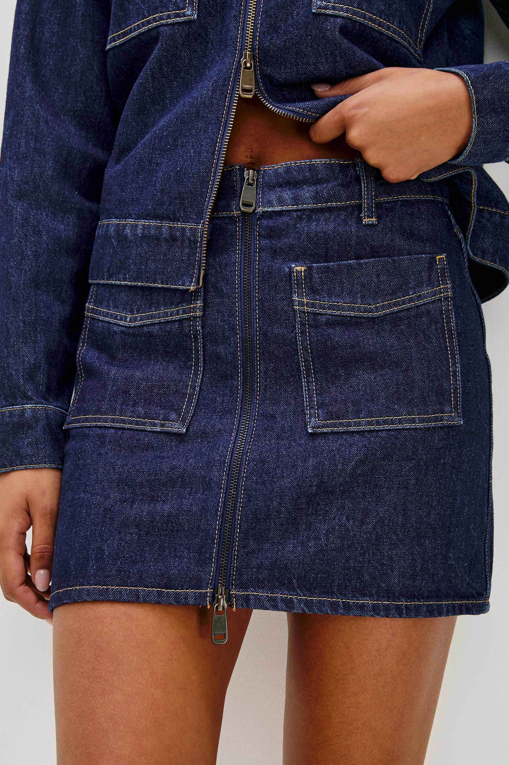 Denim jacket and skirt worn by a person on a plain background, front close up