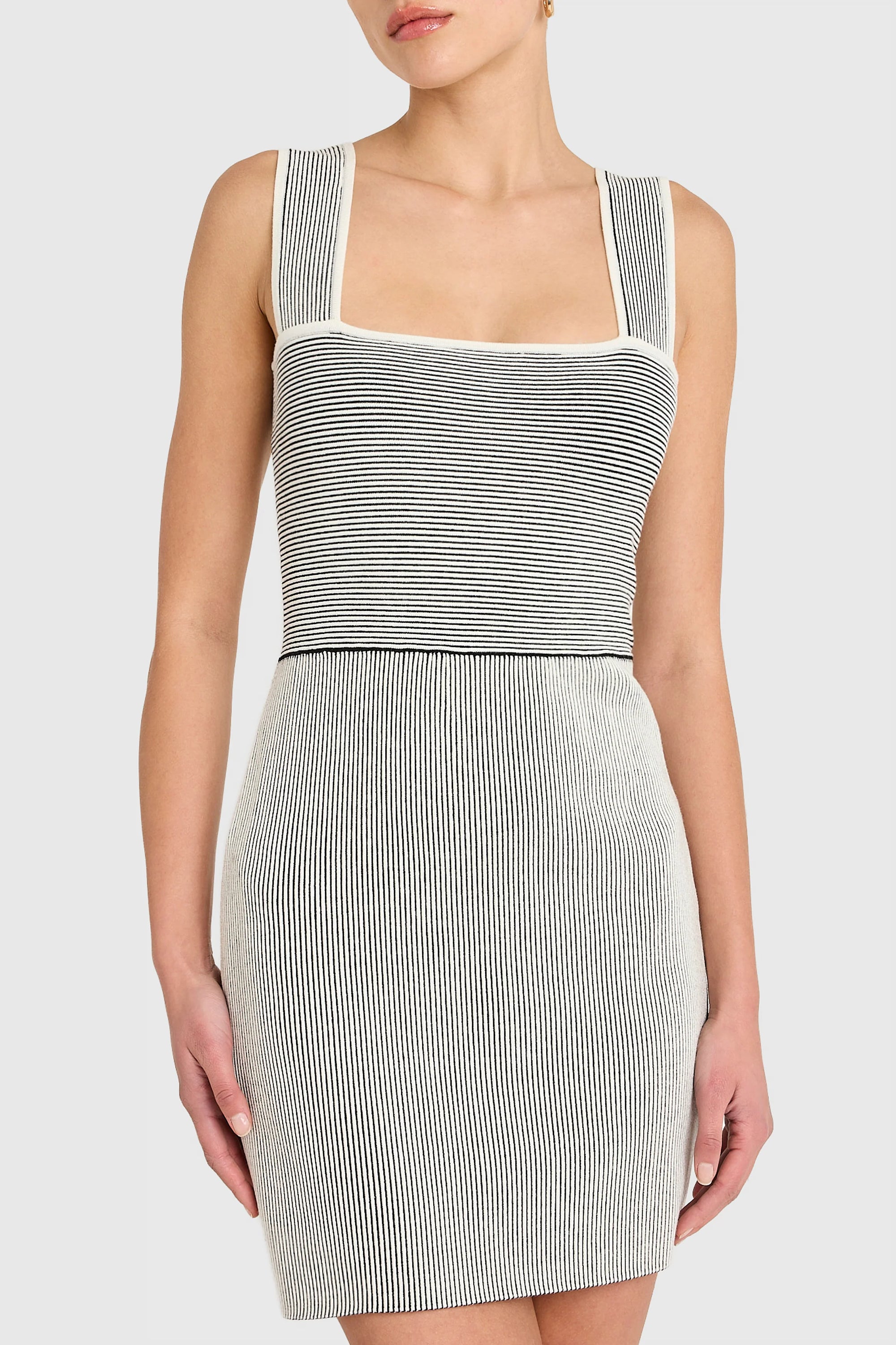 Woman wearing a sleeveless, striped dress on a white background