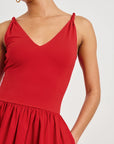 Red sleeveless dress worn by a person on a plain background detail view