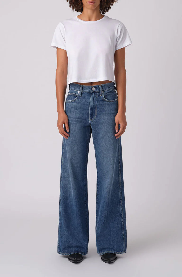 Person wearing a white t-shirt and blue jeans on a plain background