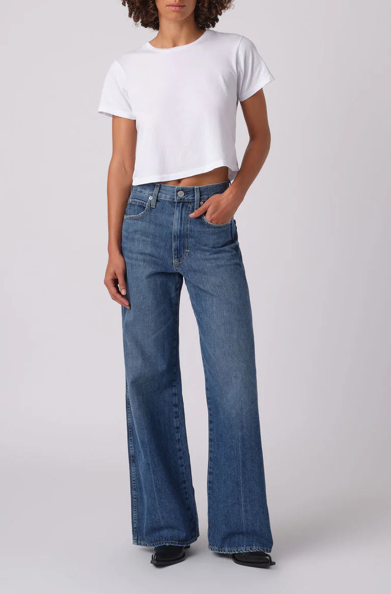 Person wearing a white t-shirt and blue jeans on a plain background