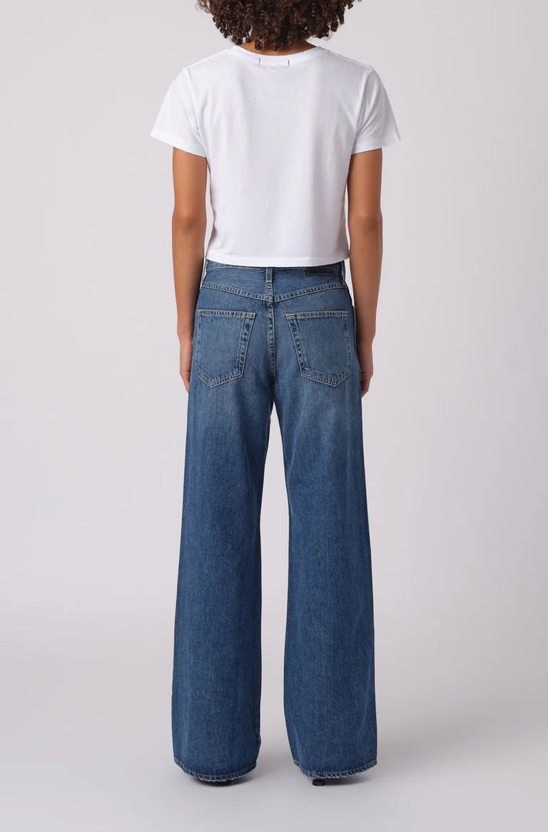 Person wearing blue jeans and a white t-shirt on a plain background