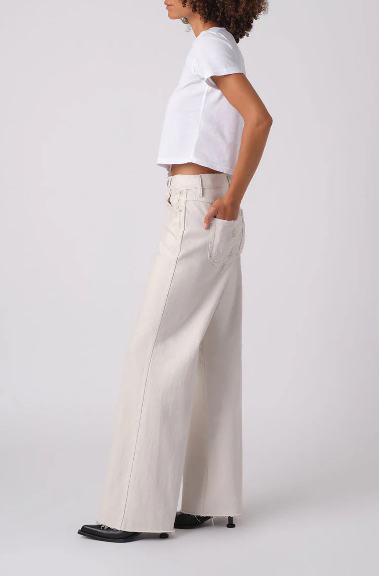 Person wearing a white shirt and beige wide-leg pants on a plain background