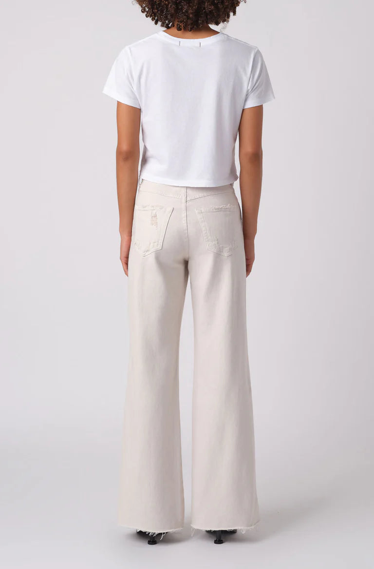 Person wearing a white t-shirt and beige wide-leg pants on a white background