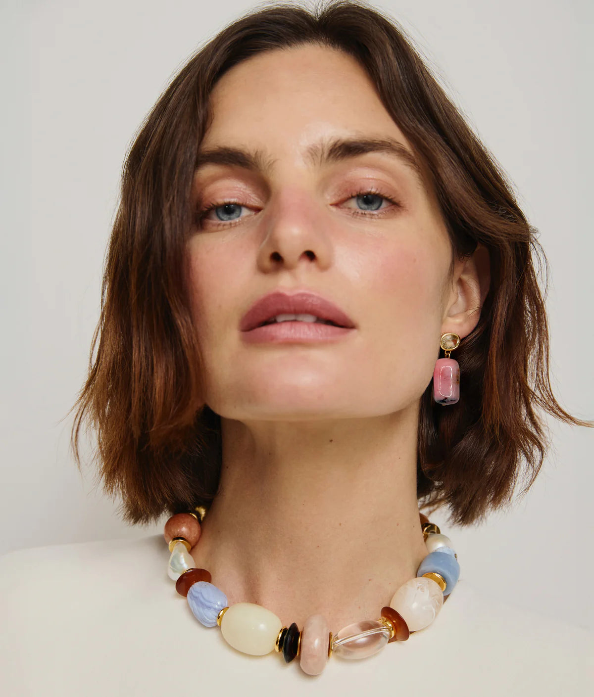 Woman wearing a colorful beaded necklace and earrings against a plain background