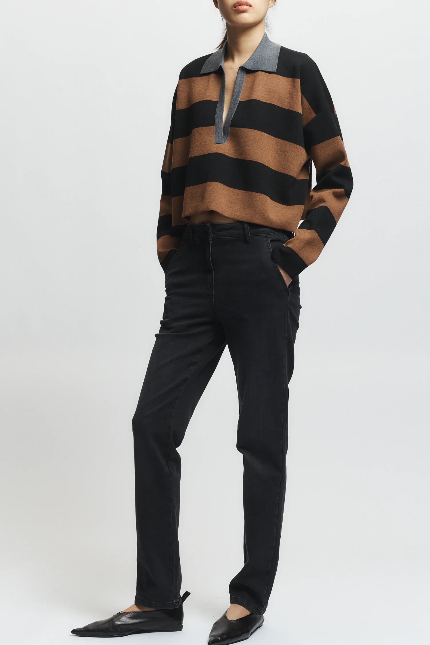 Person wearing a brown and black striped sweater with a white background