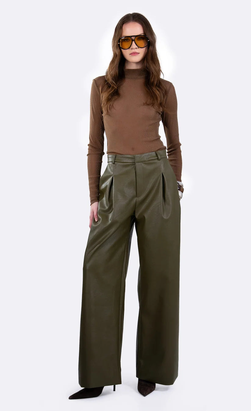 A model wearing a brown mock-neck long-sleeve top and olive green wide-leg trousers, styled with brown sunglasses and black pointed-toe heels, against a plain white studio background.