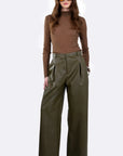 A model wearing a brown mock-neck long-sleeve top and olive green wide-leg trousers, styled with brown sunglasses and black pointed-toe heels, against a plain white studio background.