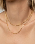 Gold chain necklace on a person's neck with a neutral background