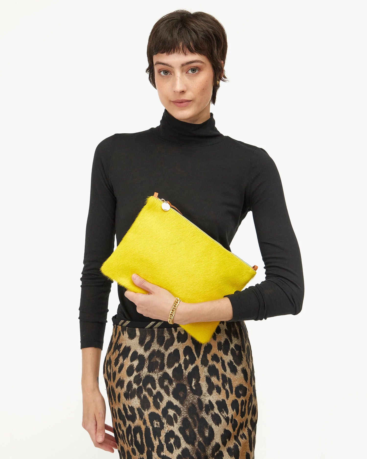Woman holding a yellow clutch bag against a white background