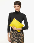 Woman holding a yellow clutch bag against a white background