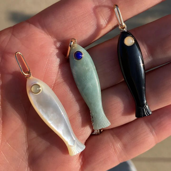 Three fish-shaped pendants on a hand