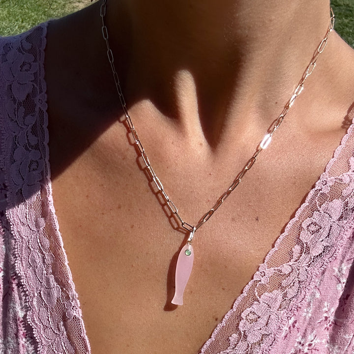 Necklace with a pink pendant worn by a person in a pink lace top.
