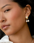Close-up of a woman wearing gold hoop earrings with pearls.