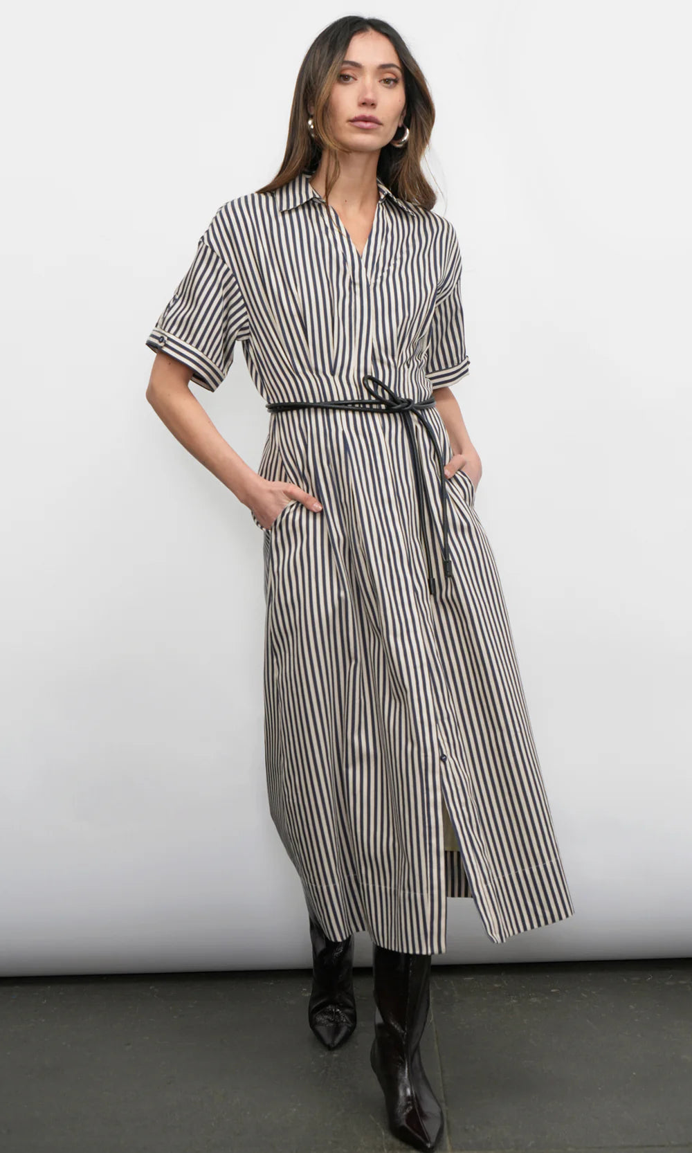 Woman wearing a navy and white striped dress with a belt against a white background