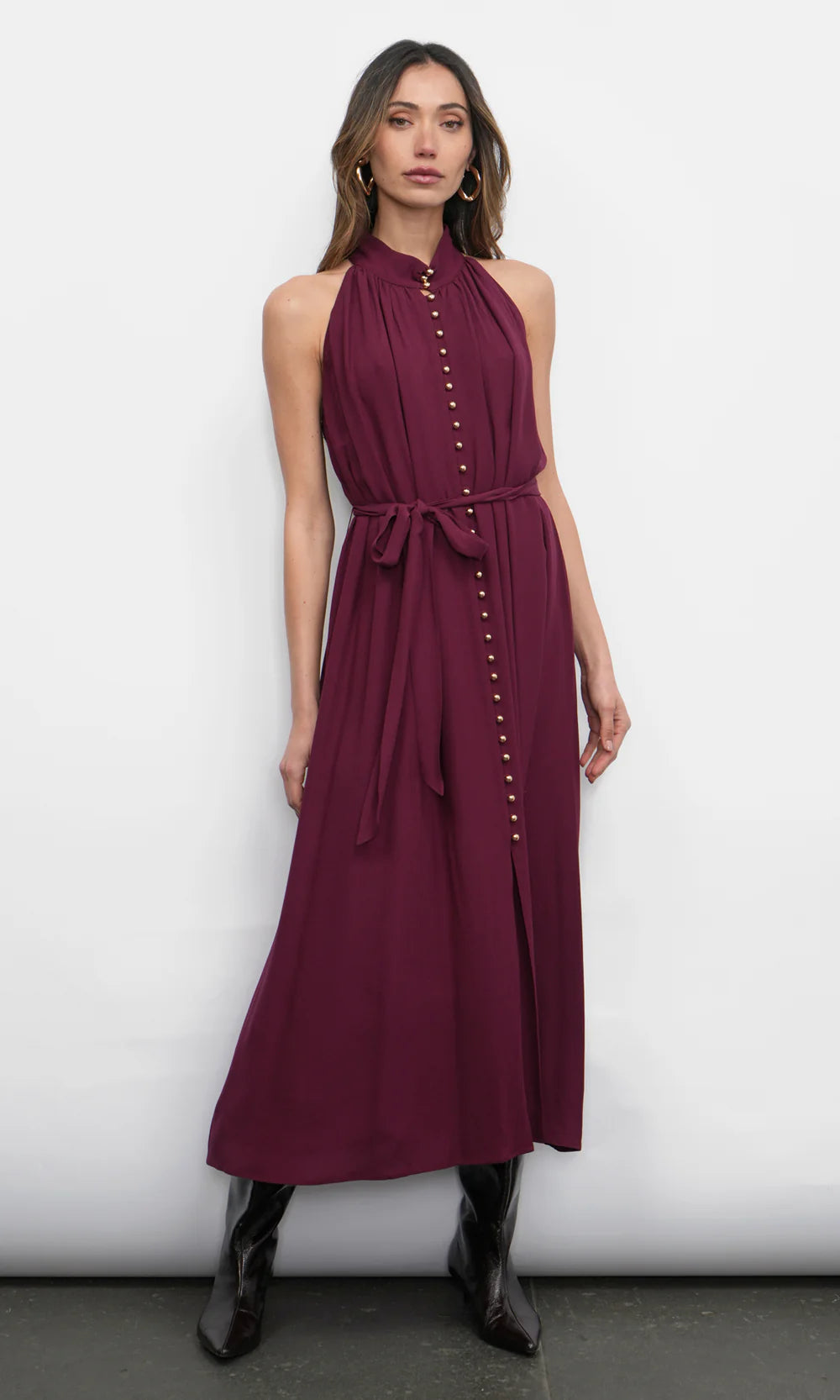 Woman wearing a burgundy dress with buttons against a white background