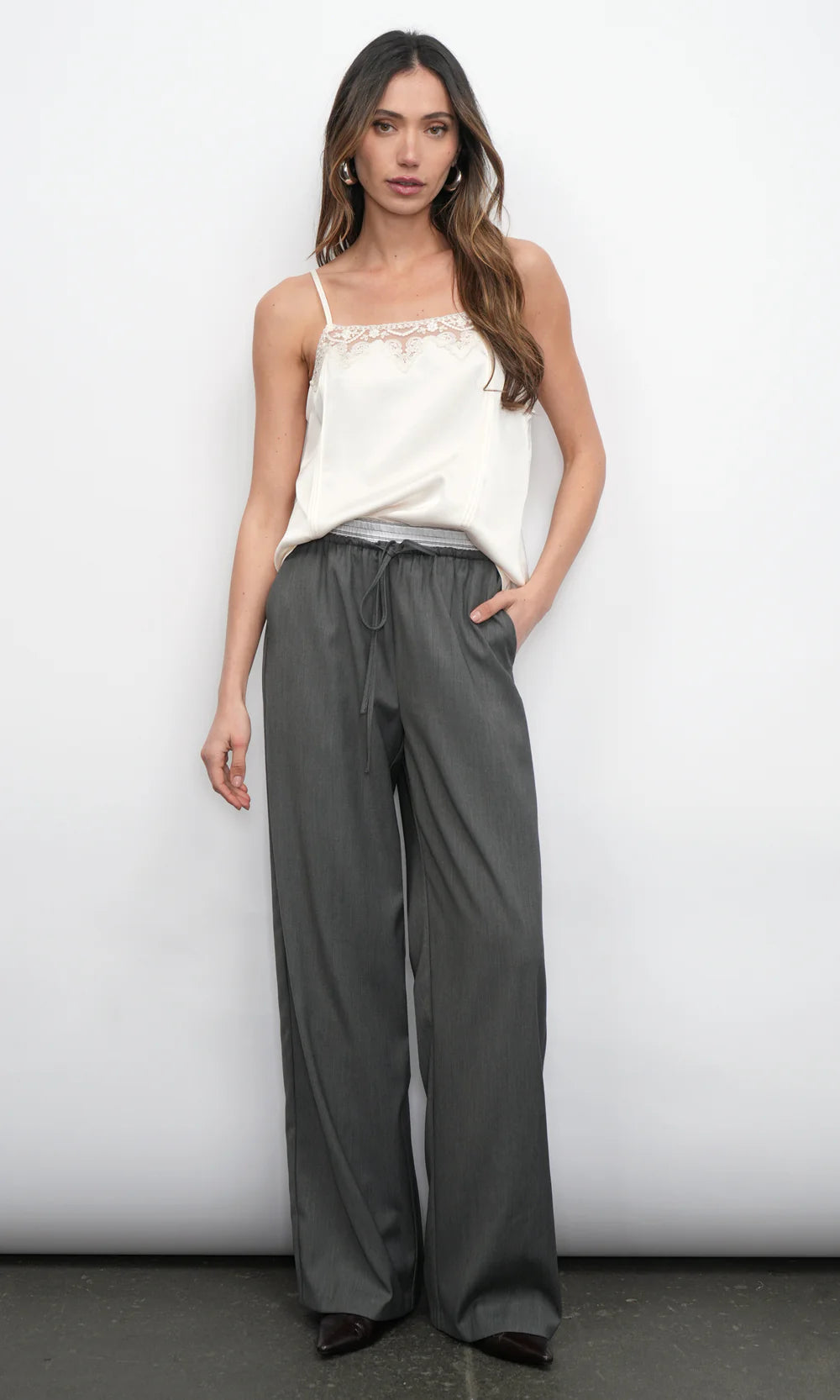 Woman wearing a white top and gray wide-leg pants against a white background