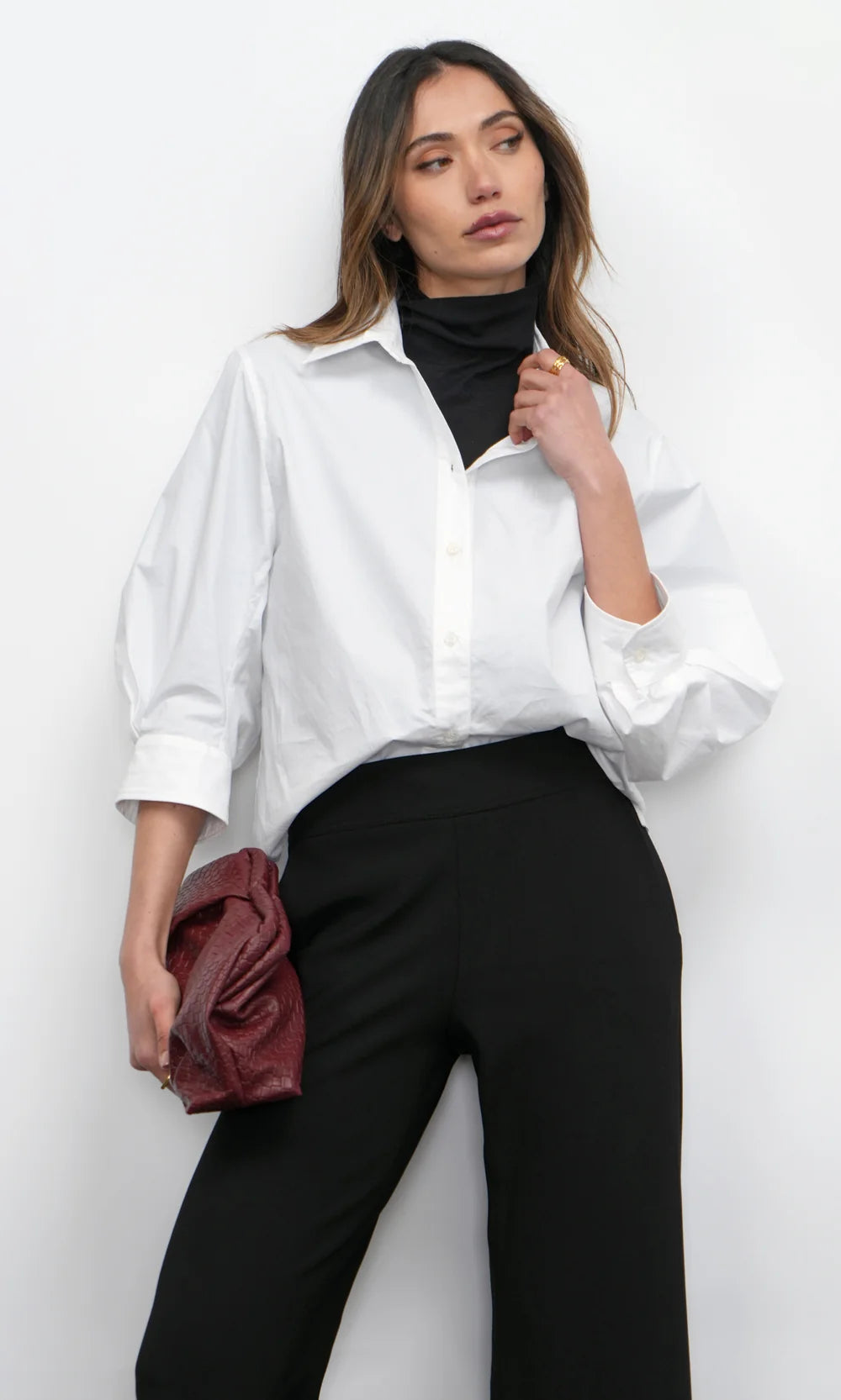 Woman wearing a white shirt and black pants against a white background