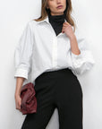 Woman wearing a white shirt and black pants against a white background