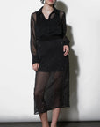 Woman wearing a black outfit with sheer elements against a white background
