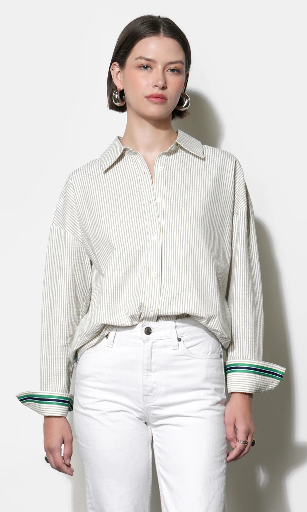 Woman wearing a striped shirt and white pants against a white background