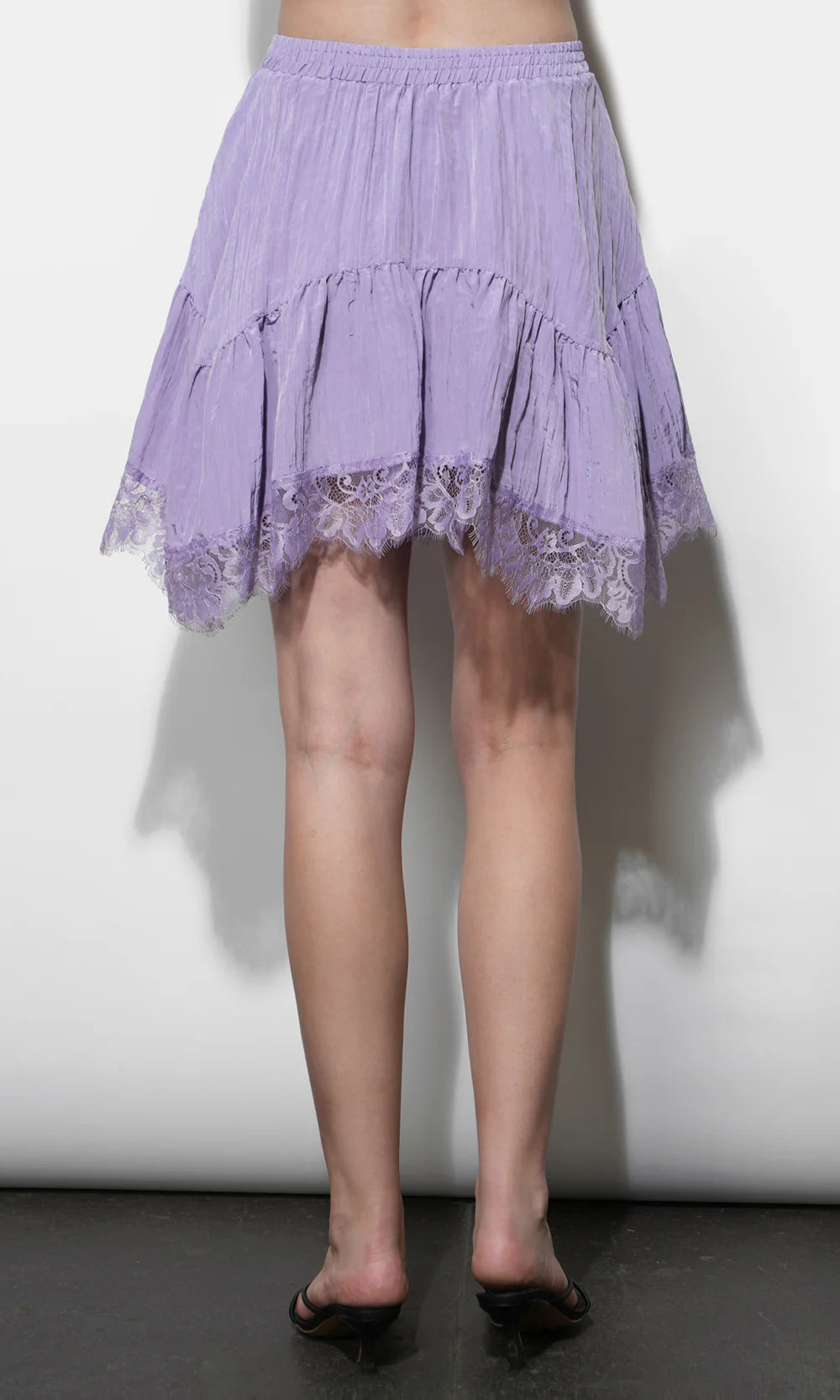Person wearing a light purple lace-trimmed skirt against a white background