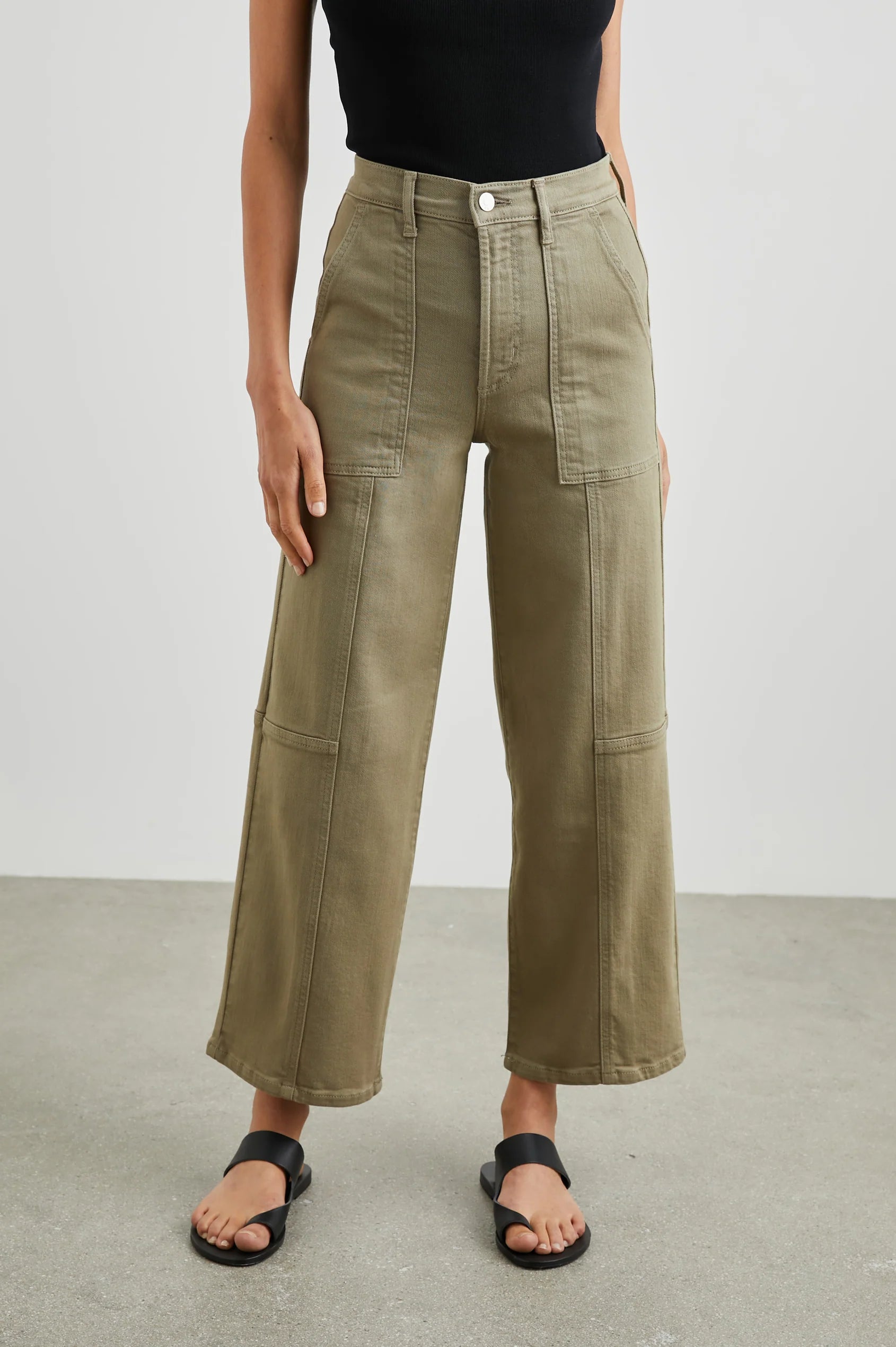 Person wearing olive green pants on a plain background