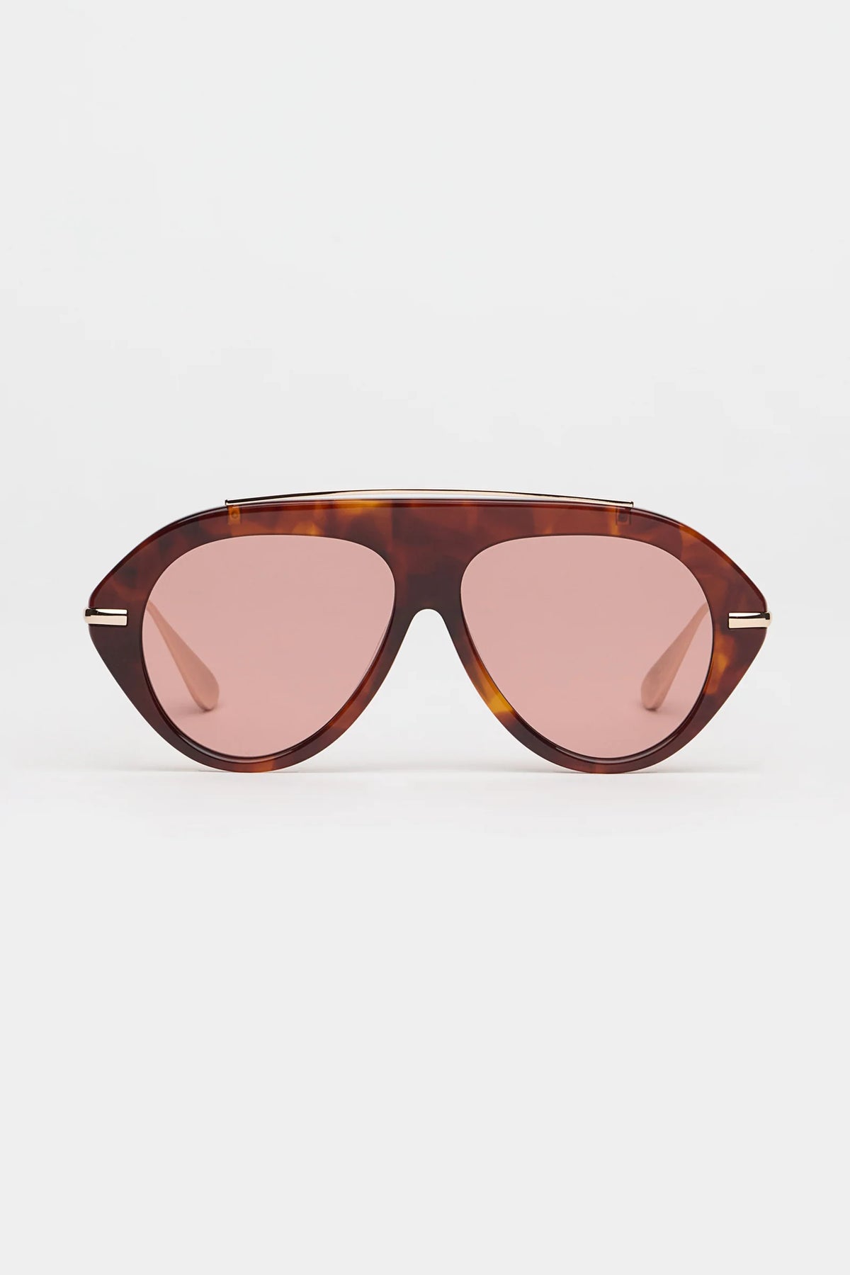 tortoise sunglasses with gold accents and light red lenses on a grey background 