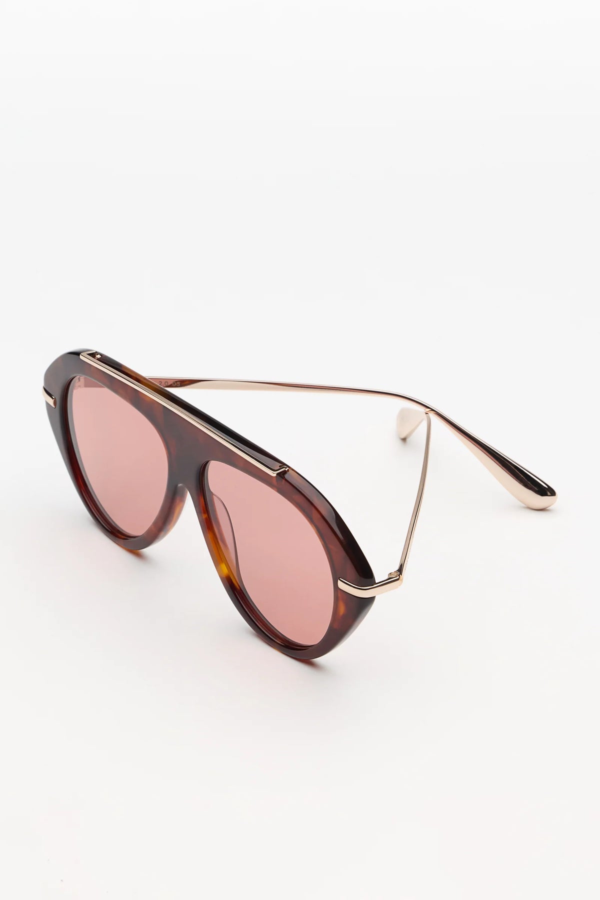 tortoise sunglasses with gold accents and light red lenses on a grey background 