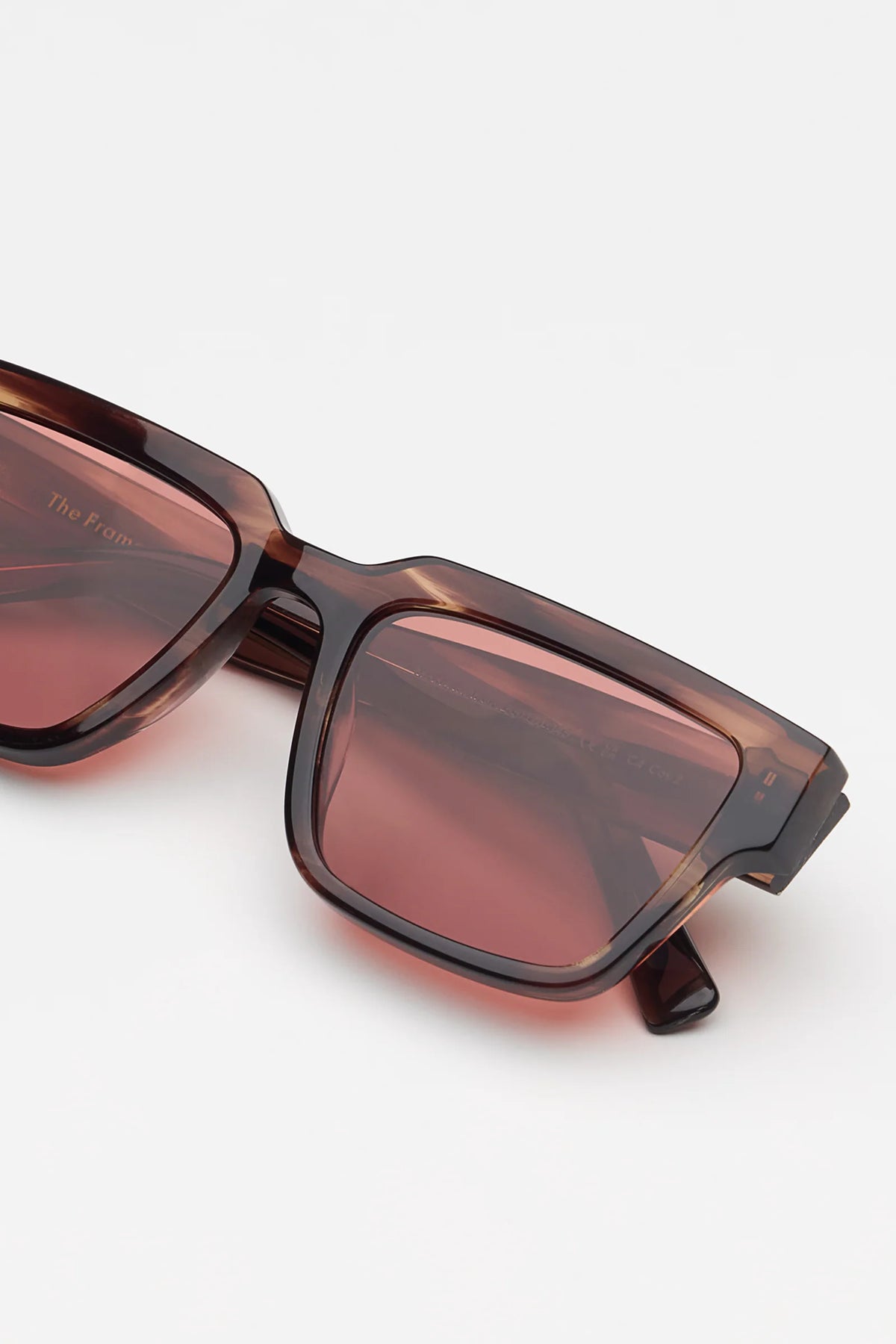 Square sunglasses with a translucent redish brown tortoiseshell frame and light red lenses, shown against a plain light gray background.