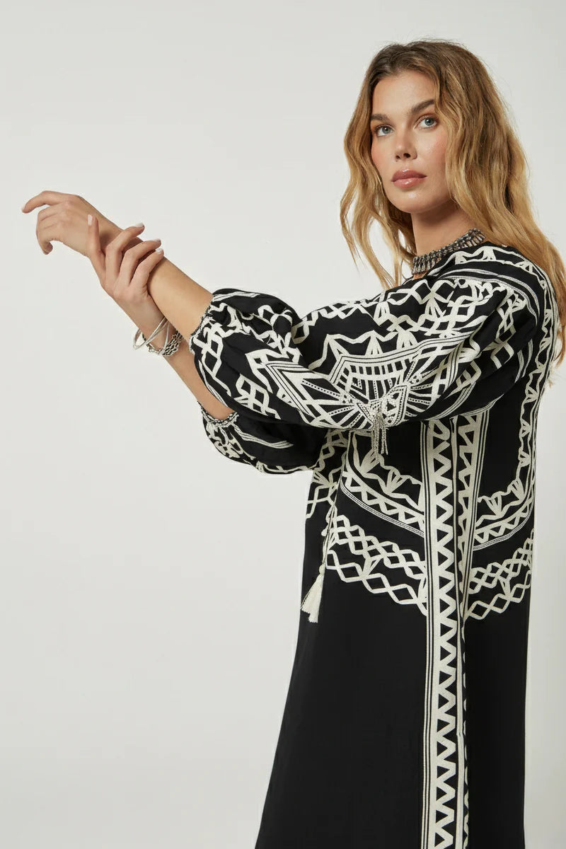 Woman wearing a black and white patterned dress against a plain background