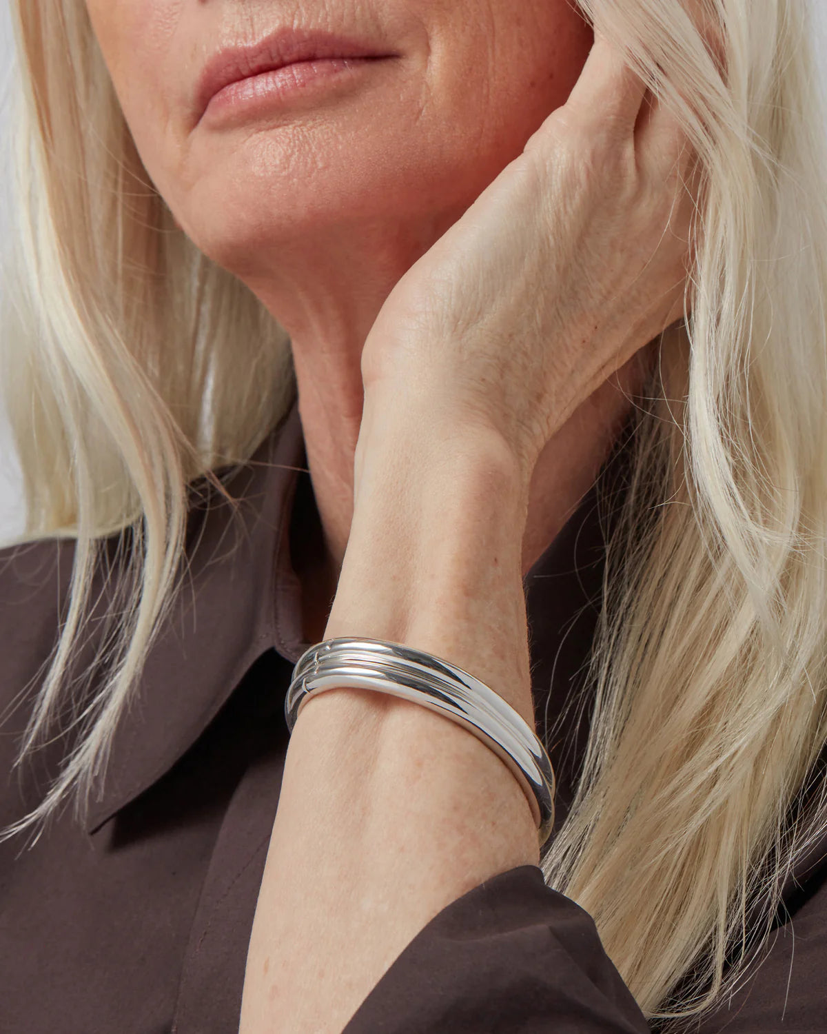 Close-up of a person wearing a silver bracelet on a plain background
