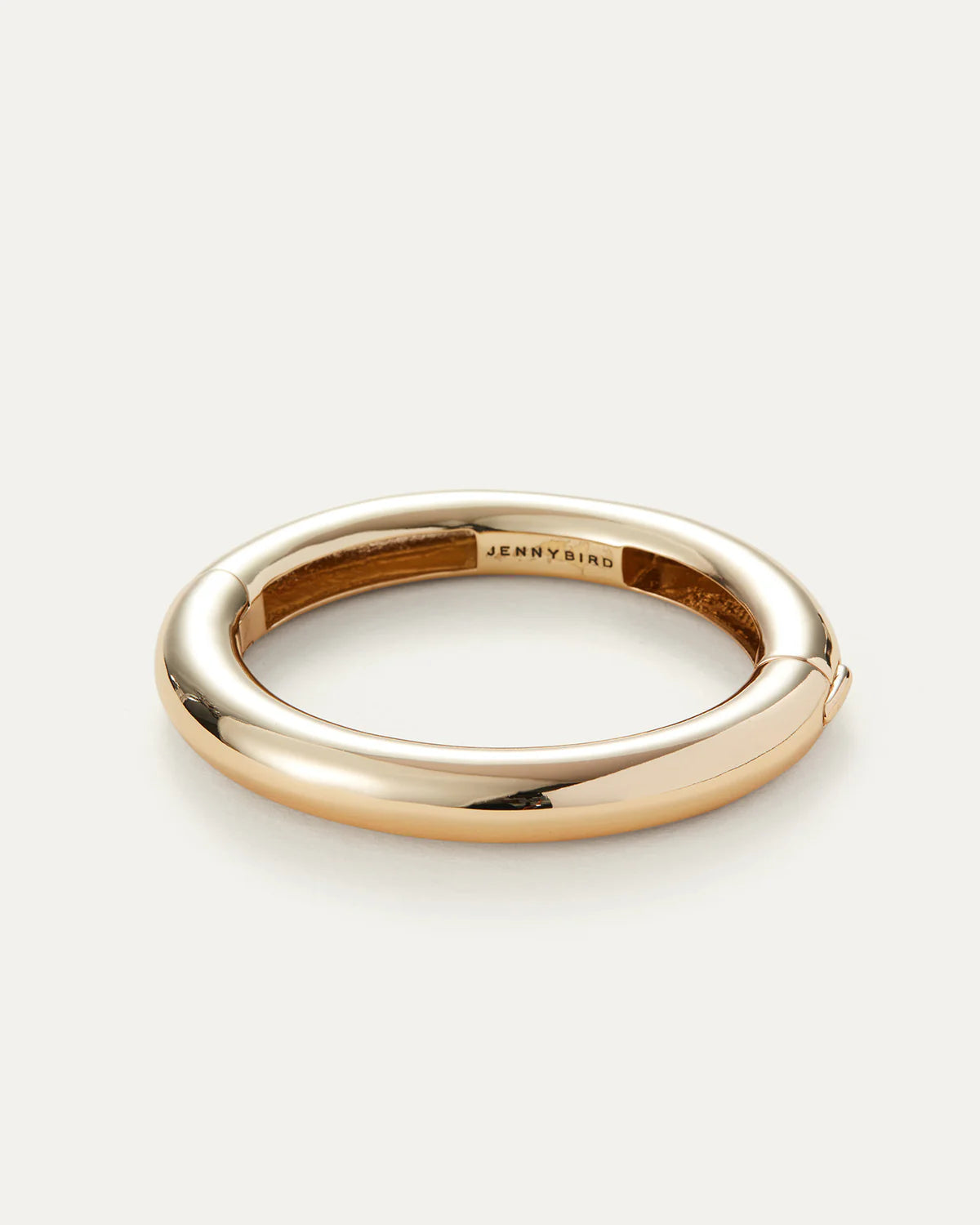 Gold ring with 'Jenny Bird' engraving on a light gray background