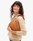 Woman holding a brown textured handbag against a white background