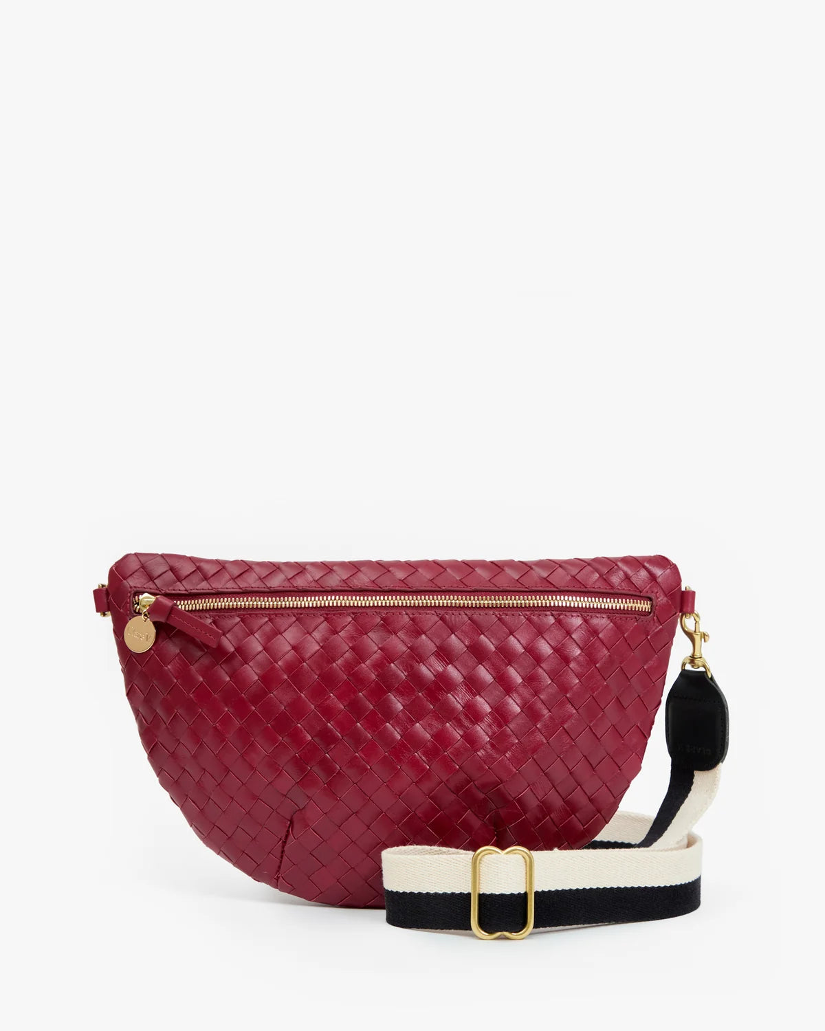 A woven leather fanny pack in deep burgundy red, featuring a gold-tone zipper, a black and white striped webbed shoulder strap with a gold buckle, and a small gold charm.