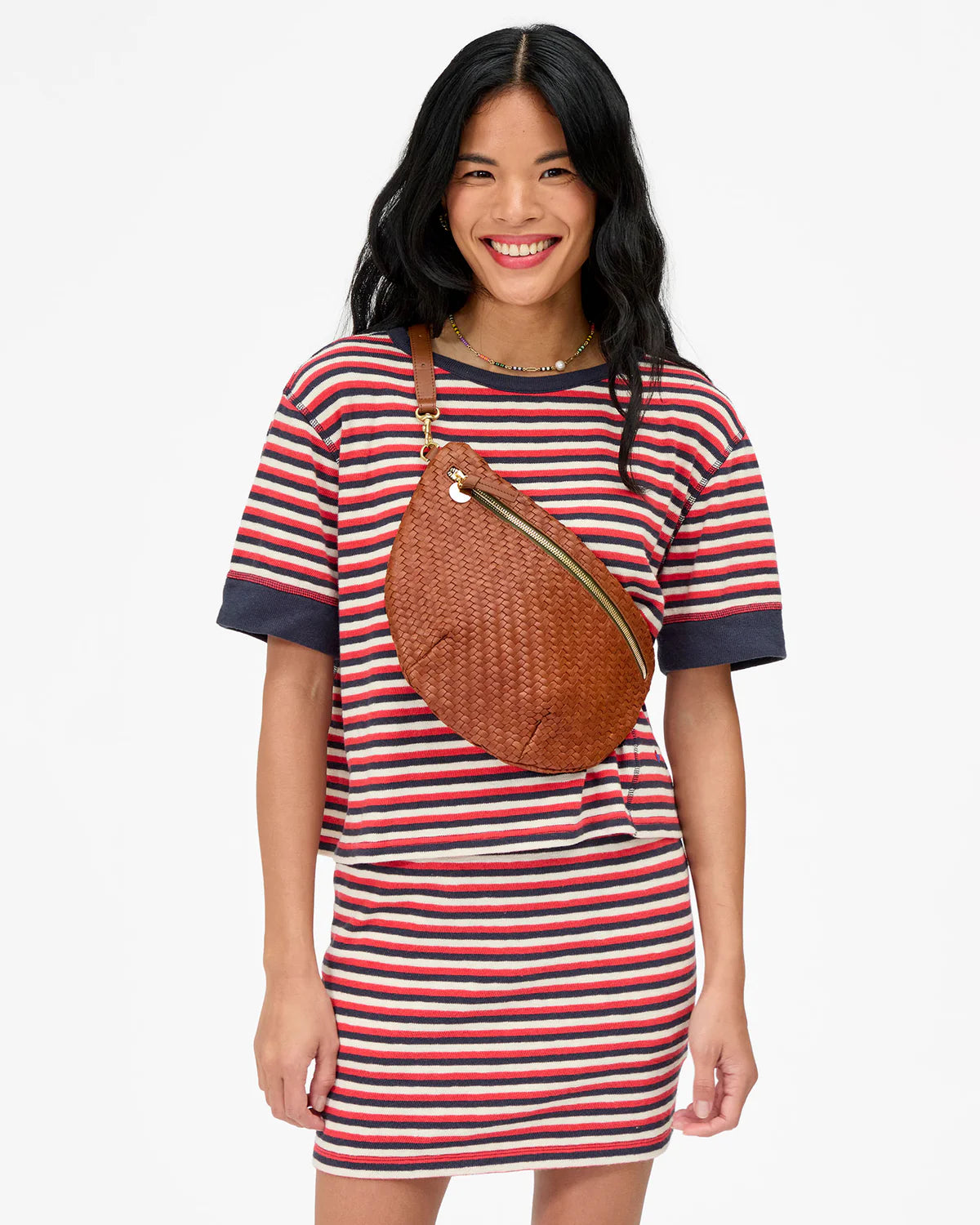 Woman wearing a striped dress with a brown bag on a white background
