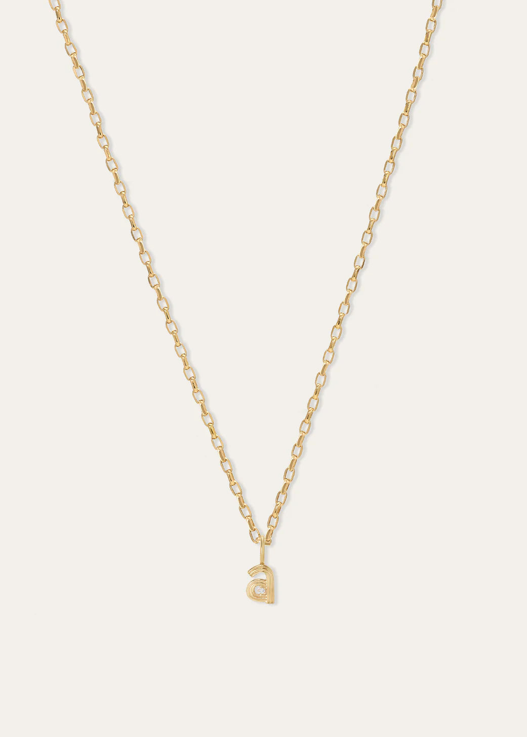 A delicate gold chain necklace with a small lowercase letter 'a' pendant, displayed against a solid off-white background.